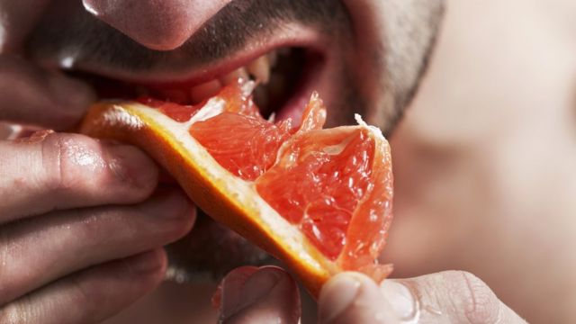 Man biting grapefruit