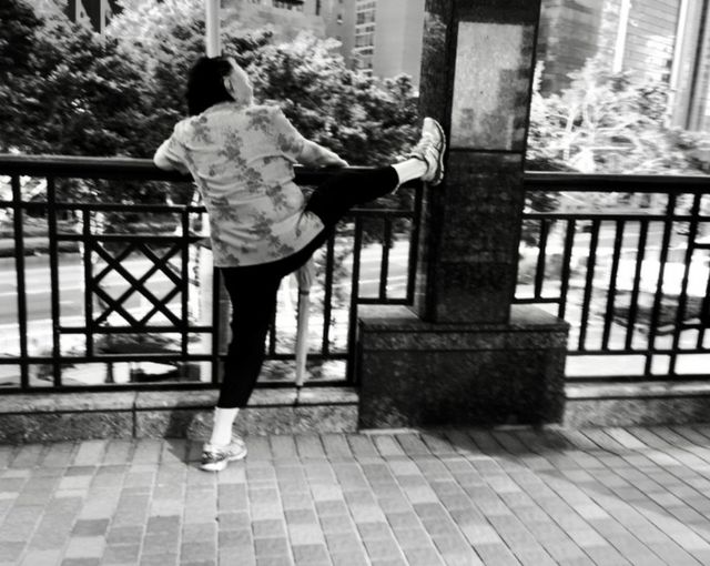 Una mujer con una pierna levantada sobre un pasamanos