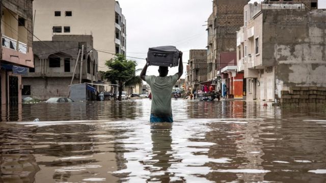 Un homme portant une valise à Keur Massar pour sortir des eaux