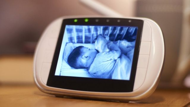 A black and white video image of a baby sleeping is seen on a baby monitor