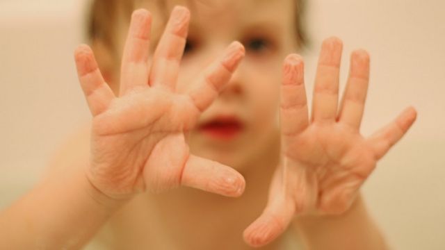 Un niño con los dedos arrugados por el agua