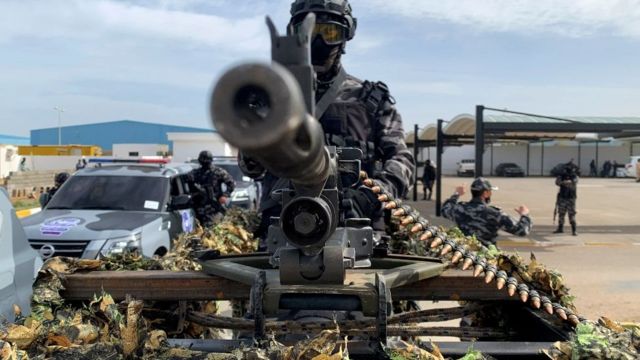 A soldier in the back of a car with a machine gun