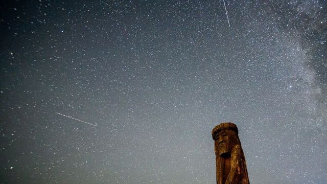 Shooting stars cross the night sky over a wooden idol near the village of Ptich some 25km away from Minsk, during the peak of the annual Perseid meteor shower on 15 August 2015.