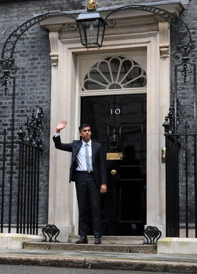 رئيس الوزراء البريطاني المعين حديثاً ريشي سوناك يلوح بيده لدى وقوفه خارج مبنى 10 داوننغ ستريت في وسط لندن في 25 أكتوبر/ تشرين الأول2022