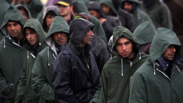 ギリシャ北部イドメニで雨の中、封鎖された国境検問所の前に並ぶ人たち（8日）