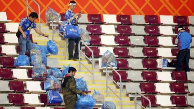 Japan fans clean the stadium following the victory over Germany