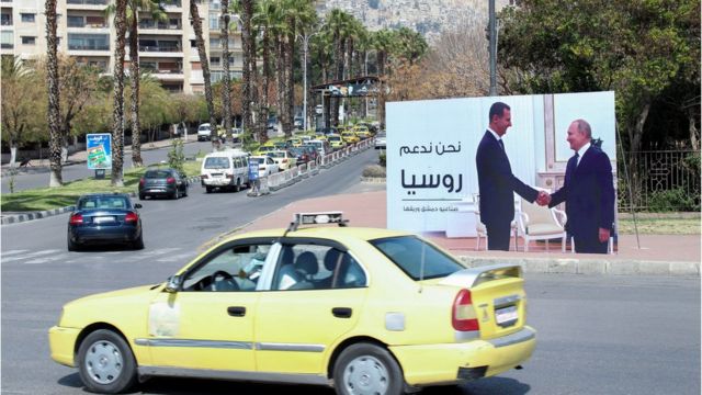 ملصق يصور الرئيس السوري بشار الأسد وهو يصافح الرئيس الروسي فلاديمير بوتين في أحد شوارع دمشق