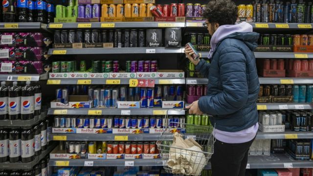 Un joven compra bebidas energizantes en un supermercado