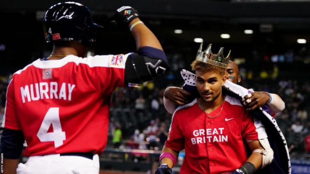 Harry Ford is presented with a crown and robe after scoring a home run in Great Britain's win over Colombia at the World Baseball Classic