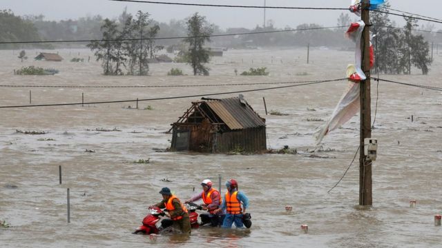 Người dân dắt xe máy qua cánh đồng ngập trắng ở Hà Tĩnh, nơi bão Doksuri tràn qua hôm 15/9/2017.