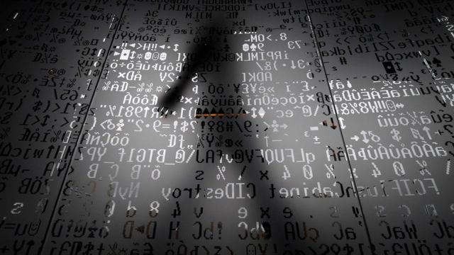 Sombra de un hombre tras códigos informáticos