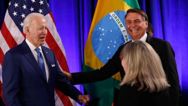 Biden e Bolsonaro. Atrás deles, bandeiras dos EUA e do Brasil