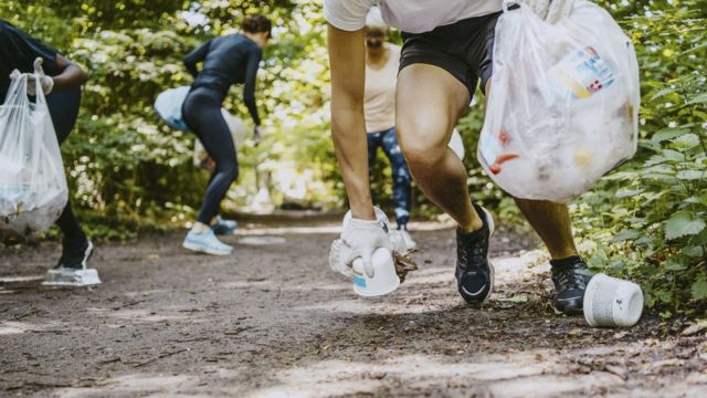 Runners picking up trash on a path through the woods