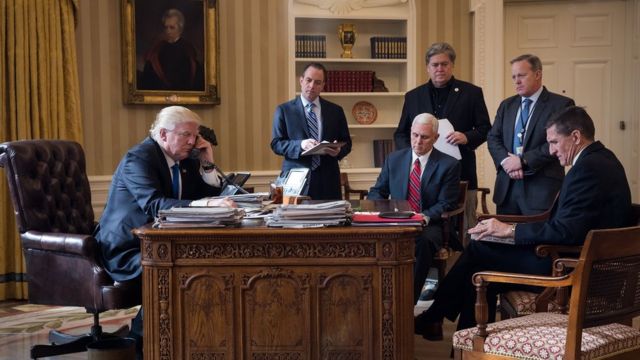 Donald Trump en la Oficina Oval hablando por teléfono con Vladimir Putin, rodeado de sus principales asesores.
