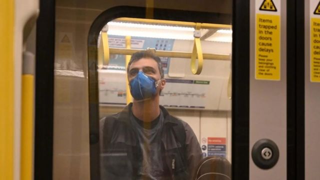 Homem de máscara viaja de pé no metro