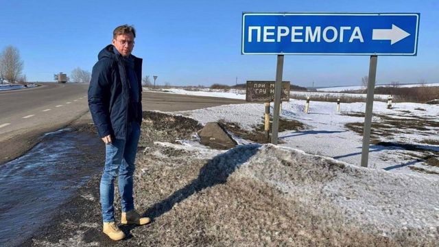 Ilya Barabanov junto a una señal de tráfico ucraniana a la ciudad de Peremoha