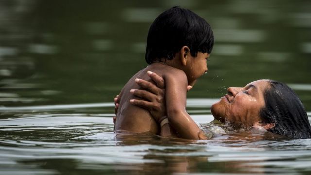 Mulher nada com criança pequena em rio em Palmas, no Tocantins