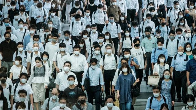 Kerumunan penumpang kereta api di Tokyo dengan masker menutup wajah mereka.