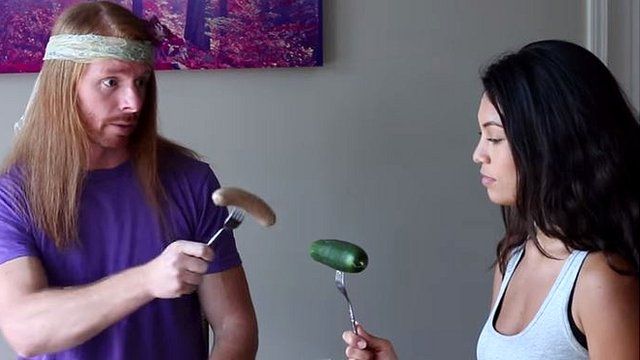Youtuber JP Sears parodying being a vegan. Here you can see him holding a sausage, talking to a woman holding a cucumber.