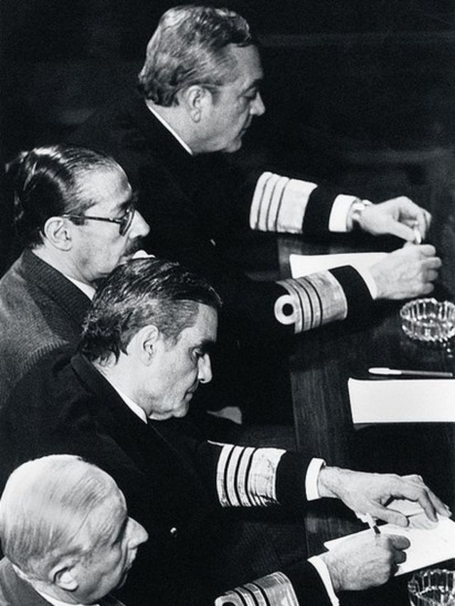 Ao centro, dois dos comandantes mais poderosos do governo militar, Rafael Videla (de óculos) e Emilio Massera (escrevendo)