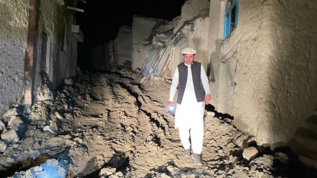 Seorang pria berjalan dalam kegelapan di zona gempa di Afghanistan.