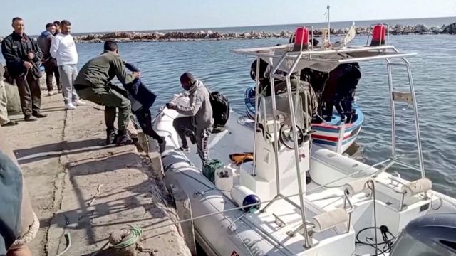 یک گارد ساحلی تونس در ماه آوریل به یک کودک کمک می‌کند تا از قایق نجات پیاده شود