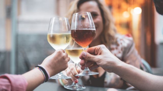 Tres personas brindan con una copa de vino