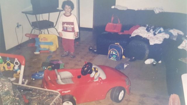 Dimy durante a infância posa perto de carro de brinquedo