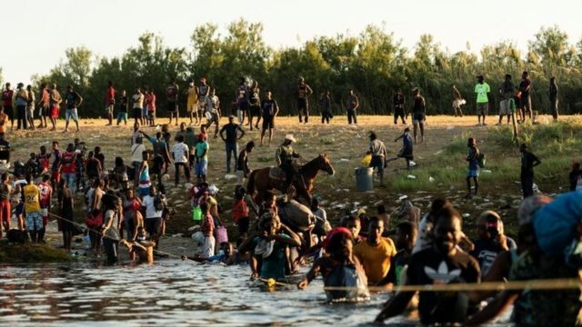 Agents de patrouille frontalière du Texas a cheval parmi des dizaines de migrants a pied