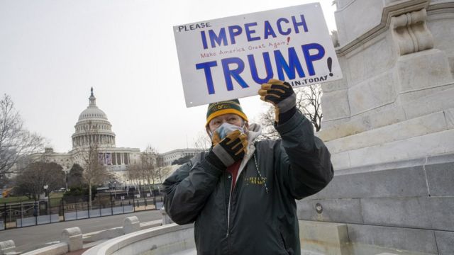 Un hombre sostiene un cartel en el que pide que se haga un impeachment a Trump