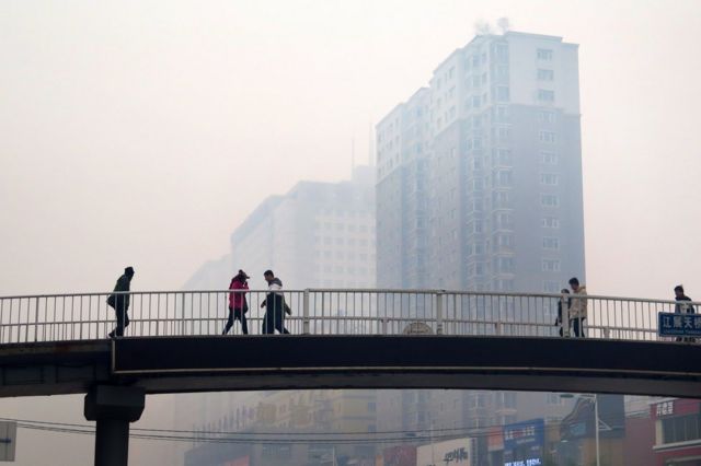 This picture taken on 8 November 2015 shows Chinese residents walking along a pedestrian bridge in Shenyang, China's Liaoning province