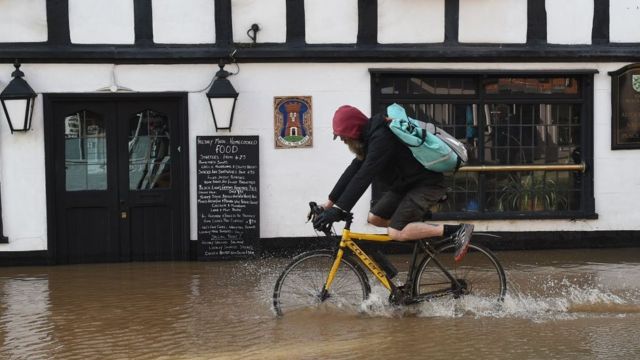 Man cycling through floodwater in Hereford