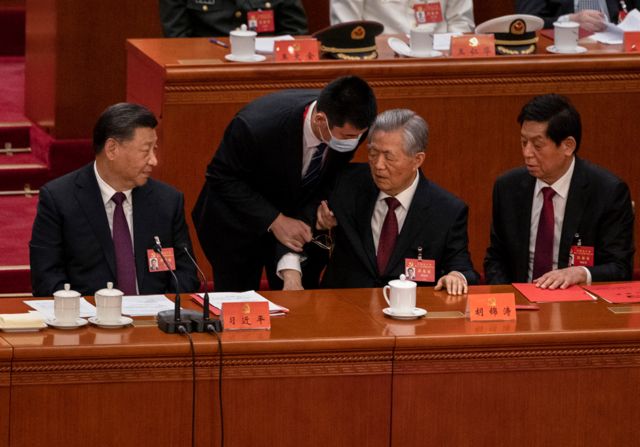 El presidente chino, Xi Jinping, a la izquierda, Li Zhanshu, y Wang Huning, a la derecha, miran mientras el expresidente Hu Jintao, en el centro, sale de la sesión de clausura del XX Congreso Nacional del Partido Comunista de China, en Beijing, el 22 de octubre de 2022.