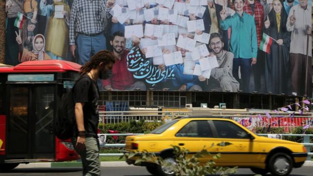 رجل يسير أمام لافتة انتخابية قبل يوم من الانتخابات الرئاسية الثالثة عشرة. طهران، إيران في 17 يونيو/حزيران 2021.