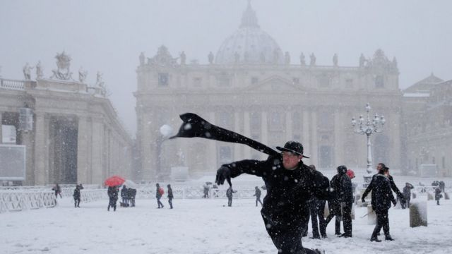 A young priest throws a snowball in St Peter's Square, Vatican
