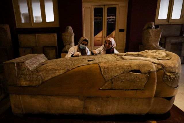 علماء الآثار يفحصون تابوتًا داخل المتحف المصري بالقاهرة.
