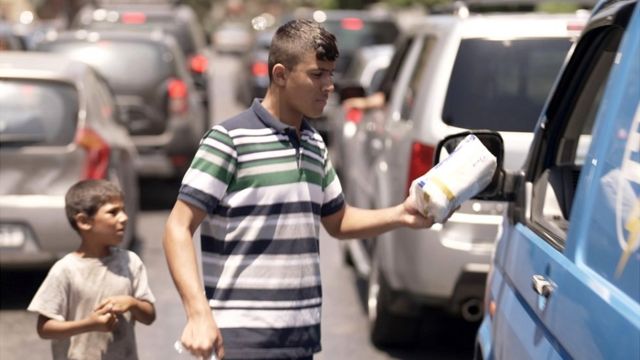 Muhammad sells tissues to passing cars in Lebanon