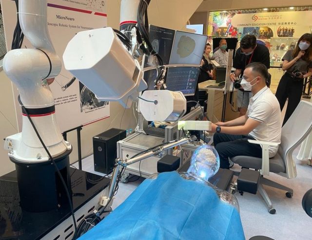 一名工作人员在香港科学园展览中演示由中国科学院香港科技创新研究院人工智能与机器人中心开发的颅内微创手术机器人系统。(photo:BBC)