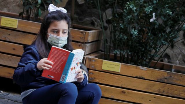 Niña leyendo en la calle de Nápoles.