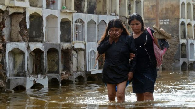 Dos mujeres caminan en Perú por una zona inundada por las lluvias.