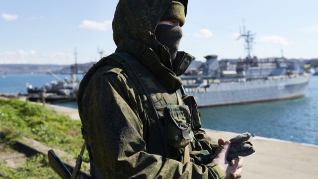 Um soldado russo parado na frente de um navio da Marinha na Crimeia