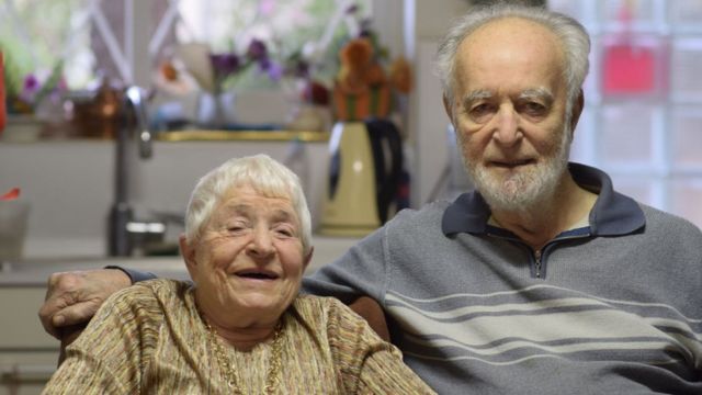 Um casal de idosos se abraça e sorri