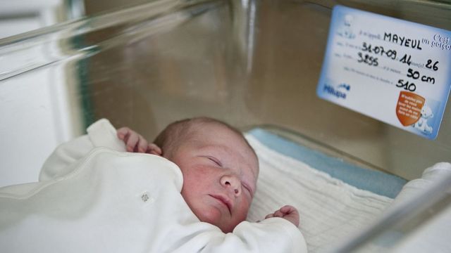 A baby with a card with his data