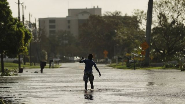 Jovem anda por rua inundada em Naples, na Flórida