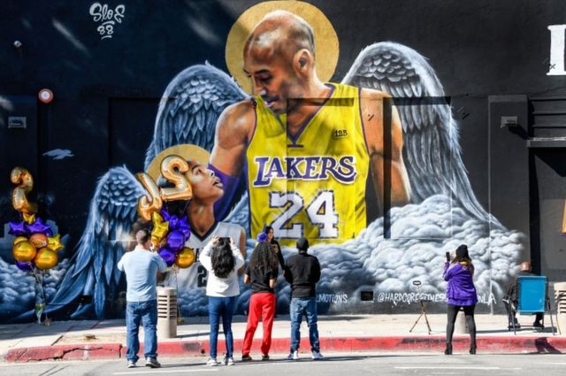 Fans gather at a mural of Kobe Bryant and his daughter Gianna, painted on the wall of Hardcore Fitness Bootcamp gym in downtown Los Angeles.
