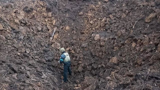 Um membro dos serviços de emergência ucranianos examina uma grande cratera de bomba no hospital infantil e maternidade Mariupol - 9 de março de 2022