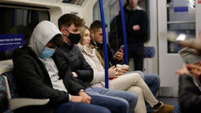 Pasajeros con y sin mascarilla en el metro de Londres.