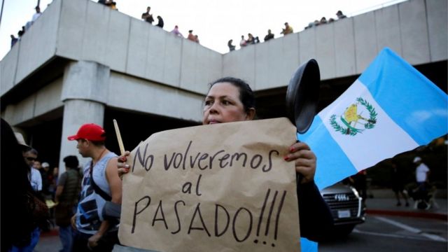 Una mujer sostiene un letrero que dice "¡No vamos a volver al pasado!" durante una protesta frente al Aeropuerto Internacional La Aurora en apoyo de Yilen Osorio, miembro de la comisión de la ONU contra la corrupción (CICIG) detenido a su llegada al aeropuerto el sábado, en la ciudad de Guatemala, Guatemala, 6 de enero de 2019.