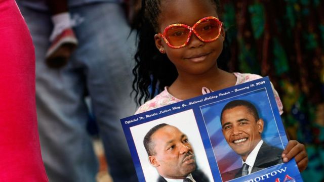 Niña con letrero con las imágenes de Martin Luther King y Barack Obama