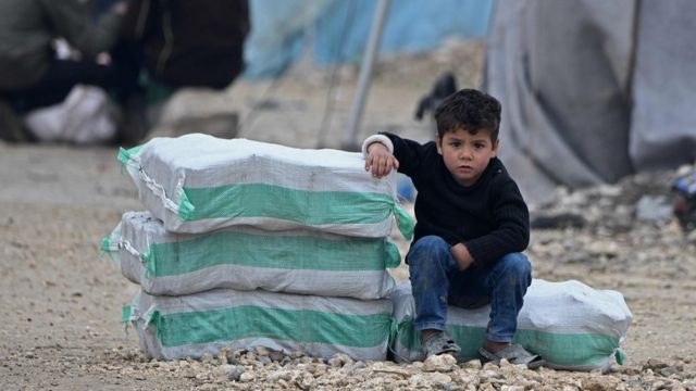 мальчик сидит рядом с пакетом гуманитарной помощи